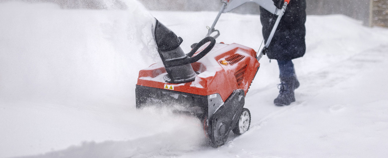 woman using single-stage snow blower on walkway