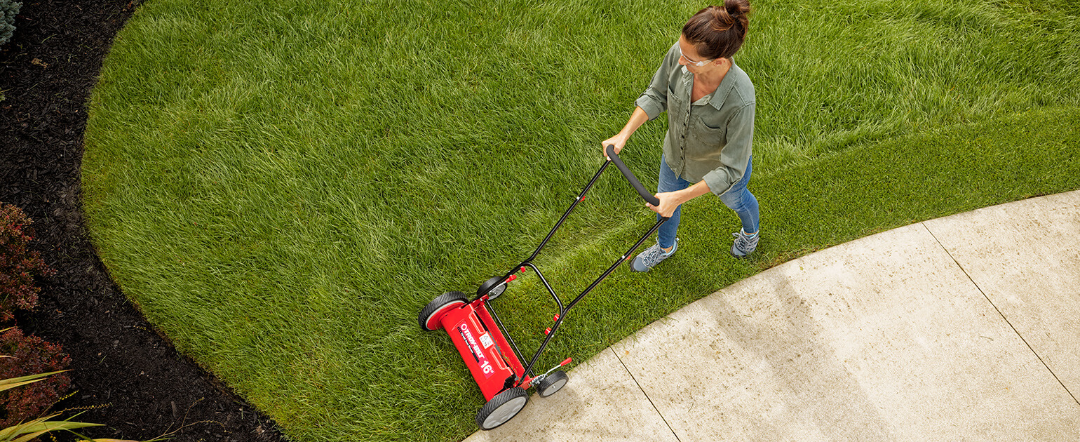 woman using a reel mower on her lawn