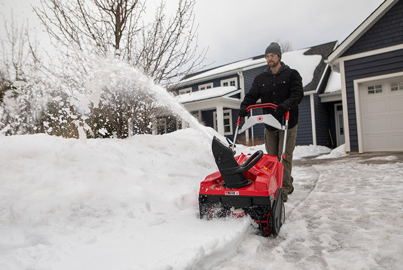 Man clearing snow by pile with single stage snow blower