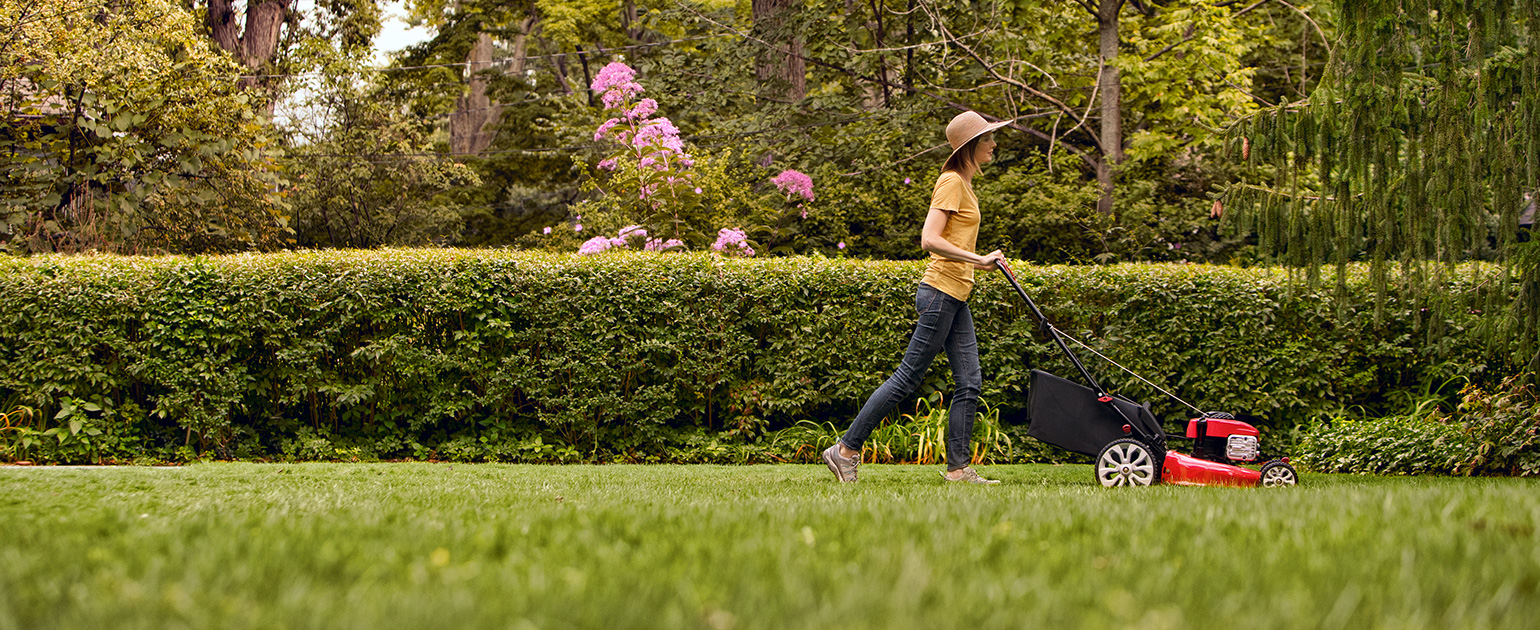 woman mowing her backyard garden