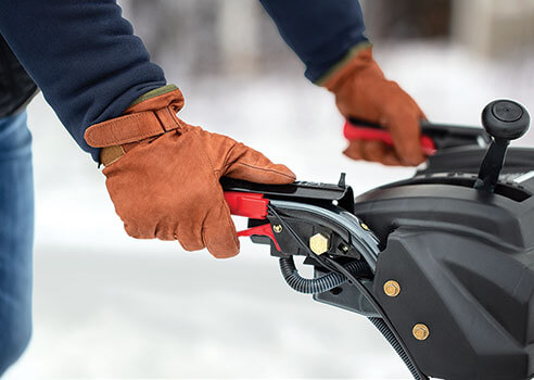person holding the heated hand grips on a snow blower