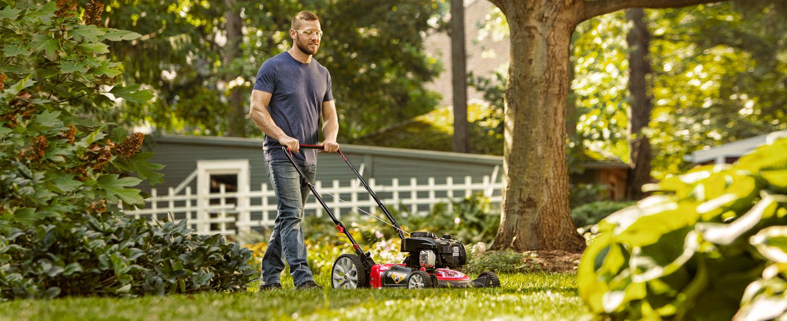 man mowing his backyard with walk-behind mower