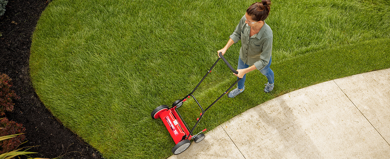 woman using a reel mower on her lawn
