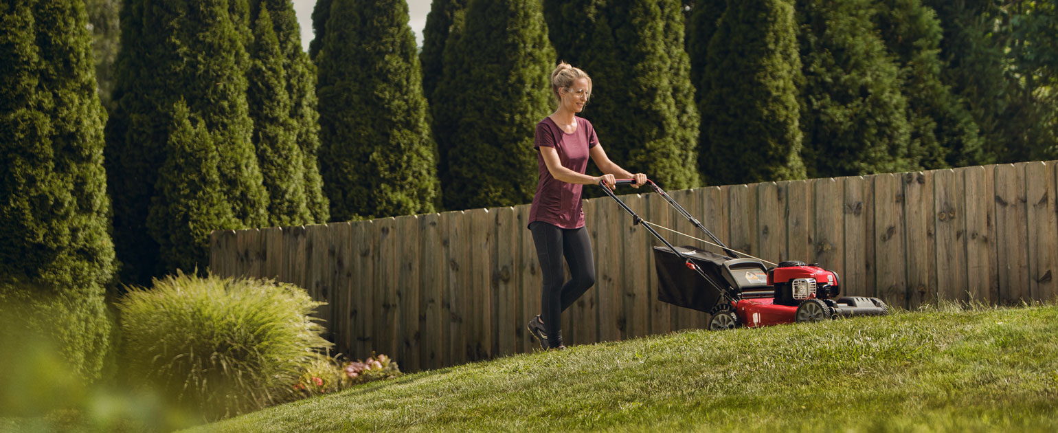 woman mowing her lawn with walk-behind mower
