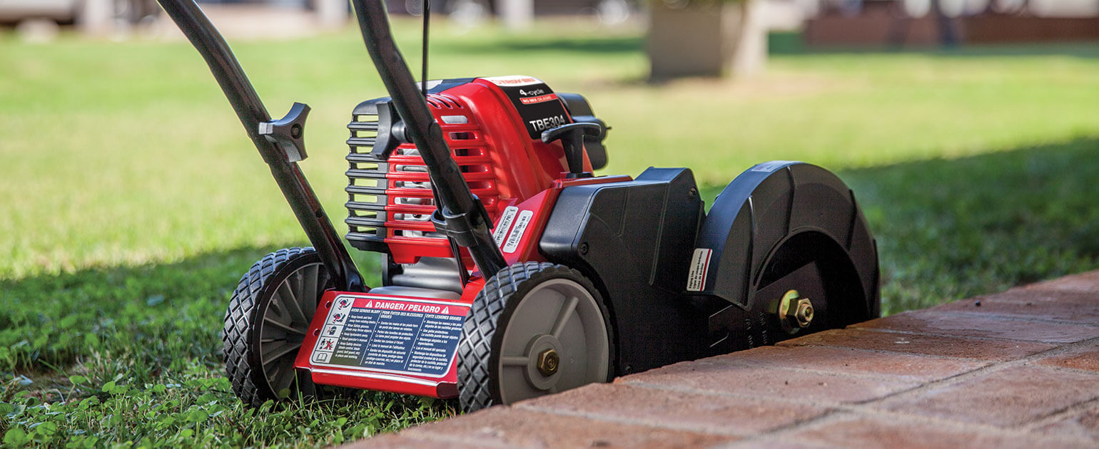 Troy-Bilt edger being used to edge grass beside brick patio