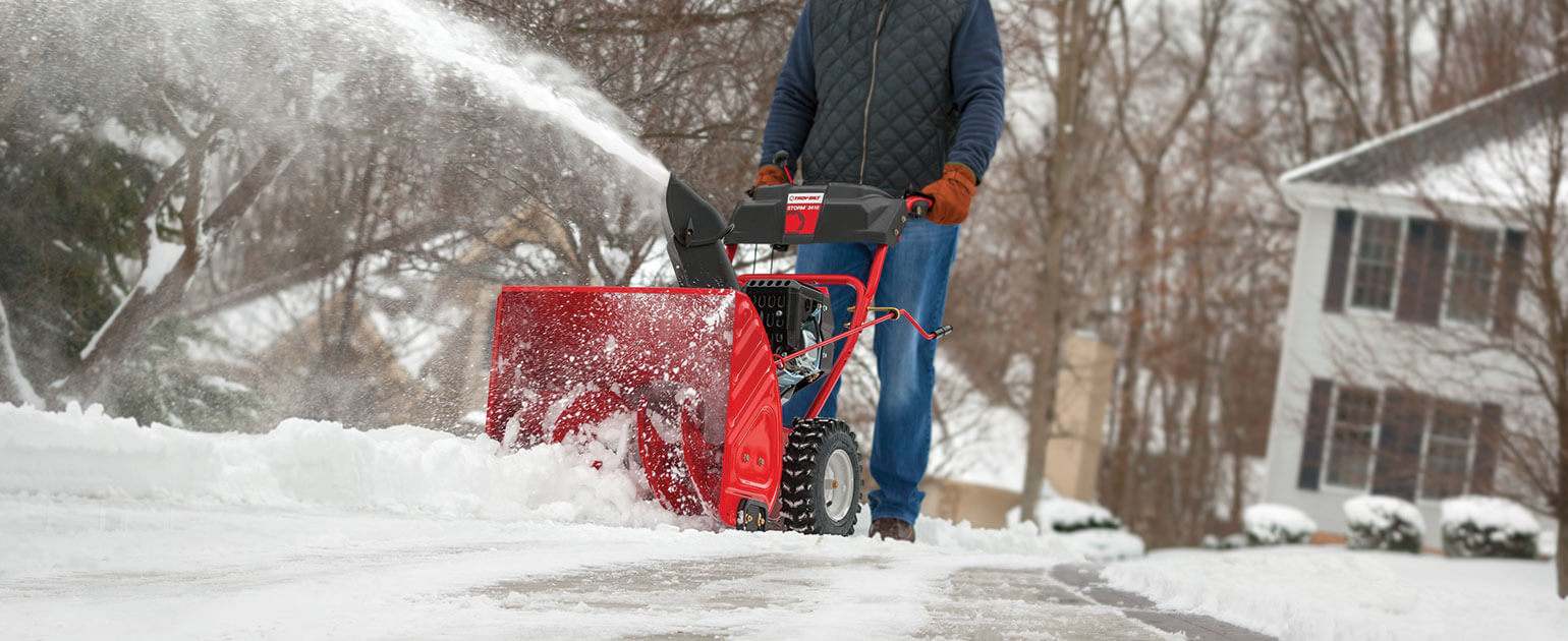 Person using two-stage snow blower on lane-way